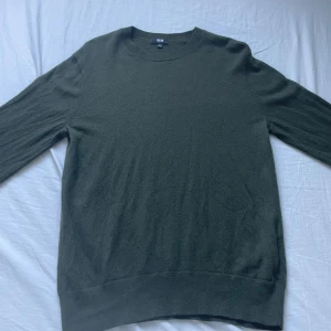 Mörkgrön Kashmir tröja från Uniqlo - En stilren mörkgrön kashmir tröja från Uniqlo i storlek S. Tröjan har rund halsringning och långa ärmar, perfekt för alla årstider. Materialet är mjukt och skönt mot huden, och den enkla designen gör den lätt att matcha med dina favoritjeans eller sneakers. Skick 10/10 använd 2 gånger 