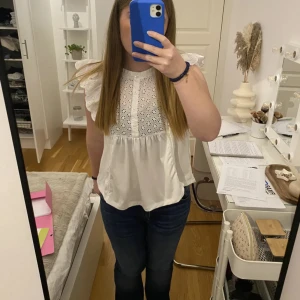 Vit blus med volangärmar och broderi - Supersöt vit blus med broderade blommor och volangärmar. Perfekt till vardags och fest! 