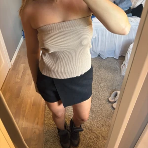 Beige ribbad tubtopp - Säljer en beige ribbad tubtopp i stretchigt material. Toppen är axelbandslös och har en tight passform som sitter snyggt på kroppen. Perfekt att styla med kjol eller jeans för en clean look. Superenkel att matcha och passar till många olika outfits. Man kan ha den som kjol också 🩷