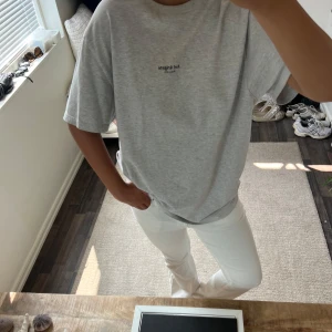 Axel arigato  - Snygg grå oversized t-shirt från Axel arigato med diskret svart text på bröstet. Modellen är klassisk med rund hals och korta ärmar, perfekt för en chill och enkel stil. Materialet känns mjukt och skönt mot huden, och passformen är loose för en avslappnad vibe.