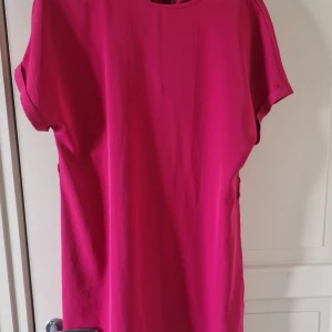Knallrosa kortklänning från SHEIN - Säljer en knallrosa kortklänning från SHEIN i storlek L. Klänningen har enkel och rak passform med rund hals och korta ärmar. Materialet känns lätt och smidigt, perfekt för dig som gillar färgstarka plagg. Supersnygg att styla med sneakers eller boots.