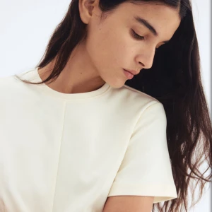 Ljusgul t-shirt med söm framtill - En stilren ljusgul t-shirt med rund halsringning och korta ärmar. T-shirten har en markerad söm som går rakt ner framtill och baktill, vilket ger en clean och modern look. Passformen är normal och materialet känns mjukt och bekvämt.