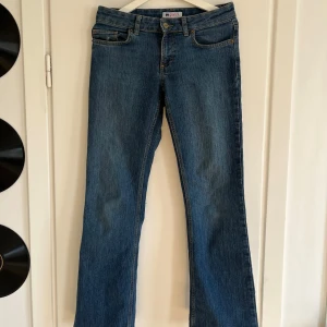 Blå bootcut jeans - Snygga blå bootcut jeans med klassisk femficksdesign och dekorativa sömmar på bakfickorna. Perfekta för en avslappnad stil. De har en knapp och dragkedja framtill.