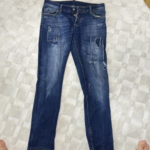 Blå jeans från Dsquared2 - Snygga blå jeans från Dsquared2 med slitna detaljer och en straight passform. De har en klassisk femficksdesign och knappar i gylfen. Perfekta för en avslappnad stil.