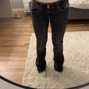 Svarta jeans från Gina Tricot Young  - Snygga svarta jeans från Gina Tricot med en klassisk femficksdesign. De har en knapp- och dragkedjestängning framtill och är perfekta för en stilren look. Jeansen är low waist bootcut i storlek 170. Lite slitna längst ner men nästan inget som syns. Pris kan diskuteras!