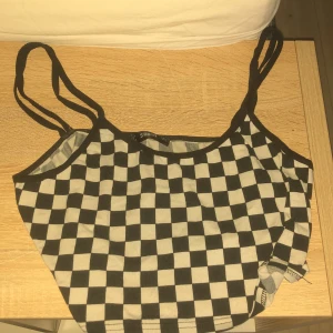 Svartvit rutig linnetopp från Shein - Säljer en cool svartvit rutig linnetopp från Shein. Toppen har smala axelband och ett klassiskt rutmönster som ger en trendig look. Perfekt för en avslappnad stil.