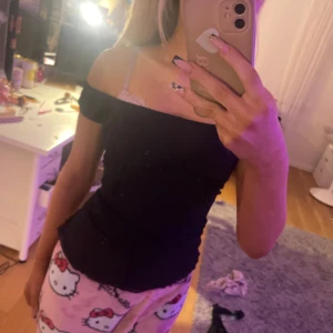 Svart topp med spetsdetaljer - Säljer en svart topp med spetsdetaljer och korta ärmar. Toppen har en smickrande passform och är perfekt för en stilren look. Den har en liten knytning i midjan för extra detalj. Man kan ha off shoulder om man vill eller som en vanlig T-shirt om man vill🫶 det är spets detaljer under bröstet och det är en tråd man knutet från baksidan fram(man få knyta hur man vill) 