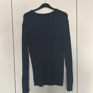 Mörkblå stickad tröja från Iconic Sport - Säljer en mörkblå stickad tröja från Iconic Sport. Tröjan har en klassisk design med långa ärmar och ribbade detaljer vid hals och ärmslut. Perfekt för kyligare dagar.