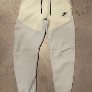 Nike Tech Fleece - Nike Tech Fleece byxor i grå/vit strl Xs men skulle även passa S beroende på preferens hur den ska sitta. Bra skick, inga tydliga defekter men ser inte helt ny ut om man kollar på nära håll.