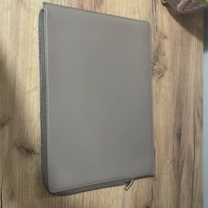 Beige datorväska med dragkedja  - Snygg och stilren beige datorväska med dragkedja. Perfekt för att skydda din laptop med stil. Enkel design som passar till alla tillfällen.