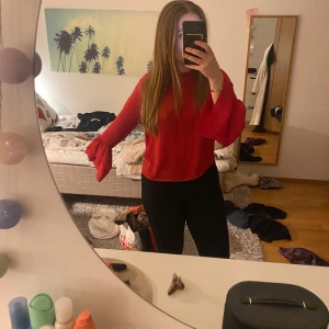 Röd blus från Gina Tricot - Säljer en snygg röd blus från Gina Tricot med volangdetaljer vid ärmslut och hals. Blusen har långa ärmar och en liten öppning i ryggen. Perfekt för att liva upp garderoben! 🔥