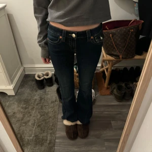 True religion jeans - Snygga mörkblå jeans med bootcut och låg midja. Byxorna har dekorativa sömmar och knappar på bakfickorna. Perfekta för en avslappnad stil.💕
