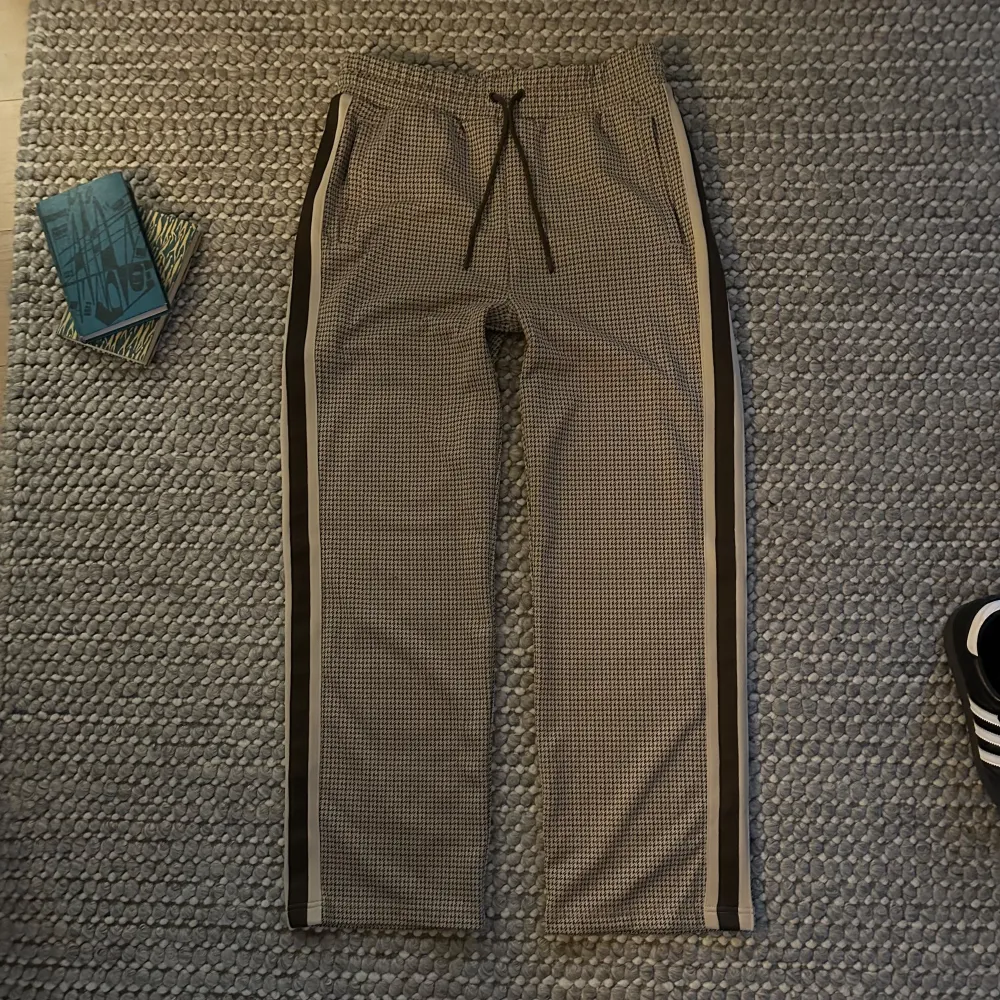 Snygga rutiga byxor från Gant med elastisk midja och snörning. Byxorna har en avslappnad passform med raka ben och sidoremsor i kontrastfärg. Perfekta för en stilren look.. Farkut & Housut.
