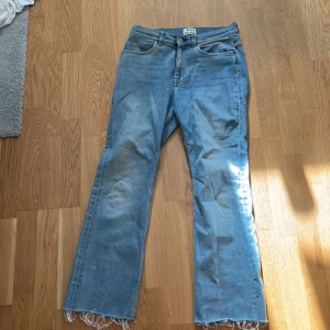 Blå jeans från Acne Studios - Snygga blå jeans från Acne Studios med fransiga benslut och klassisk femficksdesign. De har en knappgylf och är tillverkade i ett slitstarkt denimtyg. Perfekta för en avslappnad stil. Innebenslängden är 69 cm. Midjemått 36 cm.