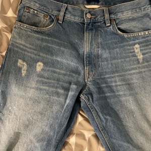 Blå jeans från GANT - Snygga blå jeans från GANT med en klassisk femficksdesign och slitna detaljer för en trendig look. De har en knappgylf och bälteshällor, perfekta för en avslappnad stil.