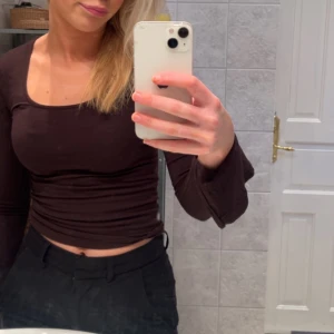 Brun långärmad croppad topp - Säljer en stilren brun långärmad topp från Gina tricot, med slits i ärmarna och croppad passform.