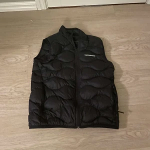 Svart dunväst från Peak Performance - Säljer en svart dunväst från Peak Performance. Västen har en dragkedja framtill och är quiltad för extra värme. Perfekt för kyliga dagar när du vill hålla stilen utan att frysa. 🖤