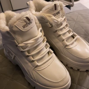 Vita boots från Miss Ninety - Snygga vita boots från Miss Ninety med fluffigt foder och snörning. Perfekta för kyliga dagar med sin robusta sula och stilrena design. De har en högre modell som ger extra värme och komfort.