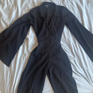 Svart byxdress från Boohoo - Elegant svart byxdress från Boohoo med långa vida ärmar. Perfekt för festlig look.  Nyskick, aldrig använd.