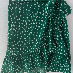 Grön blommig kjol från Only - Snygg grön kjol från Only med ett vitt blommönster. Kjolen har volangdetaljer och ett knytband i midjan för en fin passform. Perfekt för en somrig look! Kjolen är använd ett fåtal gånger men är i nyskick💕 Priset kan diskuteras💕 skriv om ni har några funderingar eller vill ha fler bilder!💕💕