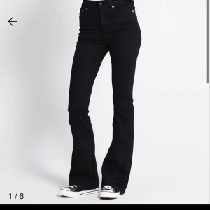 Svarta bootcut jeans - Snygga svarta bootcut jeans med hög midja. Perfekta för en stilren look. De har en klassisk design med knappar och dragkedja framtill.