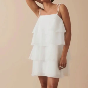 Vit Volangklänning Gina tricot  - Säljer mina söta volangklänning ifrån Gina Tricot i storlek 38. Endast använd en gång!!! Passar perfekt till dig som ska ta studenten men även till en vanlig sommardag! 💋💋nypris 799