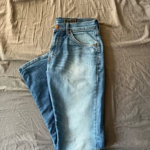 Blå jeans från Wrangler - Snygga blå jeans från Wrangler med klassisk femficksdesign och ljus tvätt. W33 L32