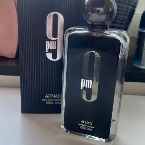 Afnan 9Pm edp 100ml - Säljer en elegant 9 PM Eau de Parfum från Afnan. Flaskan är stilren med en svart etikett och en rundad kork. Parfymen kommer i en 100 ml flaska och har en modern och sofistikerad doftprofil. Perfekt för kvällsbruk. Ca 85ml kvar