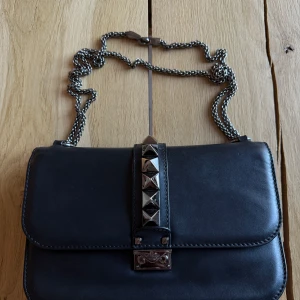  Valentino Glamlock - Valentino Garavani Glamlock väska i svart läder med silvriga detaljer. Väldigt bra skick med få täcken på användning. Säljs som den är och utan dustbag. Kvitto finns. Köptes på NK i Stockholm. Skickas ej möts upp i Stockholm.