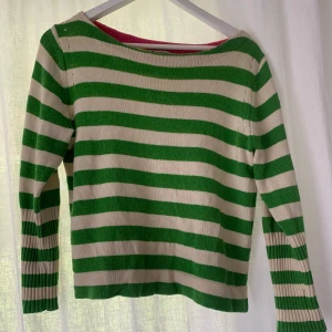 Randig stickad tröja Juicy Couture - Grön och beige randig stickad tröja från Juicy Couture. Tröjan har långa ärmar med breda ribbade muddar och en klassisk rund halsringning. 