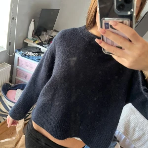 Mörkblå stickad tröja med rund hals - Mysig mörkblå stickad tröja med rund halsringning och långa ärmar. Tröjan har en loose passform och ribbade muddar vid ärmslut och nederkant. Perfekt för kyliga dagar och enkel att matcha med jeans eller kjol.