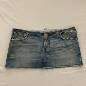 Blå jeanskjol från Pull&Bear - Säljer en kort jeanskjol från Pull&Bear i klassisk blå denim. Kjolen har slitna detaljer och fickor.  Helt oanvänd därav i perfekt skick!!
