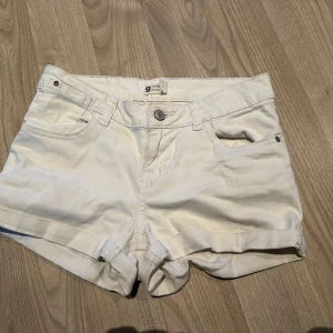 Vita jeansshorts från Gina Tricot - Snygga vita jeansshorts i klassisk femficksmodell. De har upprullade benslut, bälteshällor och knapp- samt dragkedjestängning. Perfekta för varma dagar och enkla att matcha med allt.
