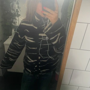 Zebramönstrad teddyjacka från H&M - Säljer en svart och vit teddyjacka från H&M i storlek S. Jackan har zebramönster, hög krage och dragkedja framtill. Den är fluffig och mjuk, perfekt för kyliga dagar. Snygg och trendig modell som sticker ut.
