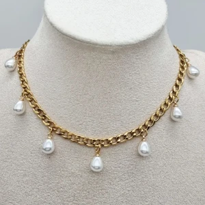 Guldhalsband med droppformade pärlor - Snyggt halsband i guldfärgad kedja med sju droppformade vita pärlor. Rostfrit stål.  Längd-40cm