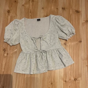 Ljusgrön blommig blus med puffärm - Supersöt ljusblå blus från Ginatricot med små blommor, puffiga korta ärmar och två knytband framtill. 