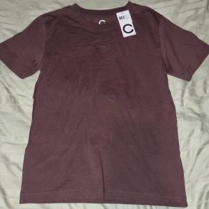 Mörkbrun t-shirt från Cubus XS - En basic mörkbrun t-shirt från Cubus i storlek XS. T-shirten är helt enfärgad med rund halsringning och korta ärmar. Tillverkad i mjuk bomull, perfekt för en clean och enkel stil.