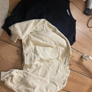 Svart och beige sweatshirt från Zink - Två stilrena sweatshirts från Zink i storlek S. En är svart och den andra är beige, båda med rund hals och ribbade muddar vid ärmslut och nederkant. Perfekt för chill dagar och enkel att matcha med jeans eller mjukisbyxor.
