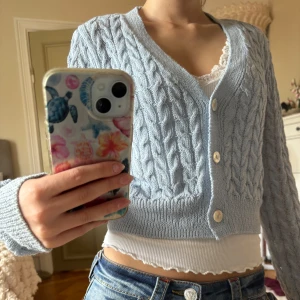 Ljusblå kabelstickad kofta från Mango - Supersöt ljusblå kabelstickad kofta från Mango med v-ringning och tre knappar framtill. Koftan är croppad och har långa ärmar, perfekt att slänga över ett linne eller t-shirt. Mysig och stilren, passar till jeans eller kjol. Skriv vid funderingar eller fler bilder🩷