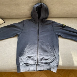 Svart hoodie från Stone Island - Säljer en svart hoodie från Stone Island med klassisk logga på vänster ärm. Tröjan har dragkedja framtill, två stora fickor och huva. Tillverkad i mjuk bomull. [Storlek Jr 12] [Skick 7/10] [Nypris: 2000kr+] [Pris: 250kr] Skriv vid behov av fler bilder eller övriga funderingar.
