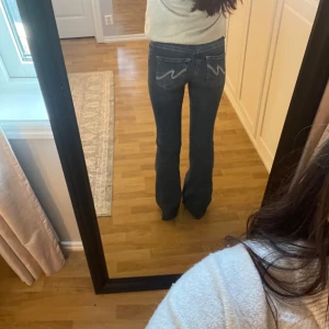 Blå bootcut jeans från Nelly, stl 36 - Snygga blå bootcut jeans från Nelly med klassisk femficksdesign och coola broderade detaljer på bakfickorna. Är använda fåtal gånger knappt tecken på använda 