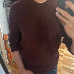 Vinröd stickad tröja med struktur - Säljer en vinröd stickad tröja från COS. Tröjan har en snygg strukturerad yta, rund halsringning och långa ärmar. Perfekt för dig som gillar en enkel men stilren look. Passar bra till jeans eller chinos. Tröjan är S, och har en lite längre passform. 