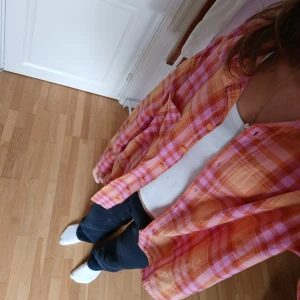 Rutig skjorta i orange och rosa från Divided - Säljer en oversized rutig skjorta från hm i orange och rosa toner. Skjortan har klassisk krage, bröstficka och knäppning framtill. Perfekt att bära öppen över ett linne.