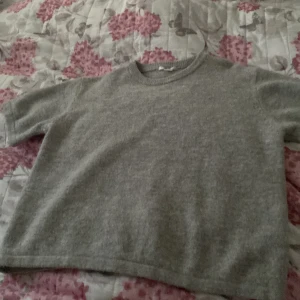 Grå stickad kortärmad tröja - En enkel och stilren grå stickad tröja med korta ärmar och rund hals. Super mysig och sitter lite oversized perfekt nu till hösten! Är 170 är själv storlek S och den passade mig