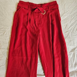 Röda kostym/finbyxor - Snygga röda kostymbyxor i luftigt tyg med hög midja och raka ben. Funkar som en färgklick både för semiformella studer och till vardags.