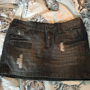 Grå jeanskjol från Gina Jeans - Assnygg grå jeanskjol från Gina Jeans i kort modell med slitna detaljer och patchad dekor framtill. Klassisk femficksdesign, bälteshällor och dragkedja. Perfekt för en edgy och avslappnad look. Midjemått: 39 cm längd: 33 cm ungefär❤️