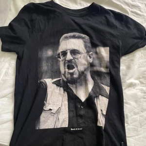 Dedicated t shirt - Cool svart t-shirt med en stor svartvit print av en man med solglasögon och skägg på framsidan. Texten 'Mark It Zero!' finns under motivet. Klassisk rund hals och korta ärmar. Perfekt för dig som gillar statement-plagg. Märket heter dedicated och tischan är i storlek S.