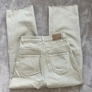 Beige jeans - Säljer ett par beige jeans med hög midja och raka ben. Jeansen har klassiska fickor, råa kanter nertill och är från lager 157. Perfekta för en clean och avslappnad look.