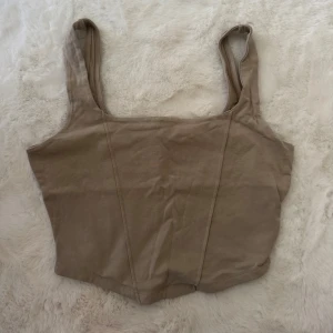 Beige croppad linnetopp Gina Tricot - Säljer en beige croppad linnetopp från Gina Tricot. Toppen har breda axelband, rundad halsringning och är figurnära i modellen. Perfekt att matcha med jeans eller kjol för en chill look.