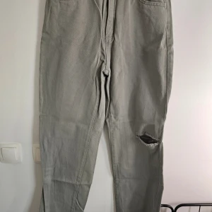 Raka byxor från SHEIN M - Gråa gröna byxor från SHEIN i rak modell med normal passform. Byxorna har klassiska fickor fram och bak samt en snygg sliten detalj vid knät. Tillverkade i ett bomullsliknande material som känns mjukt och bekvämt.